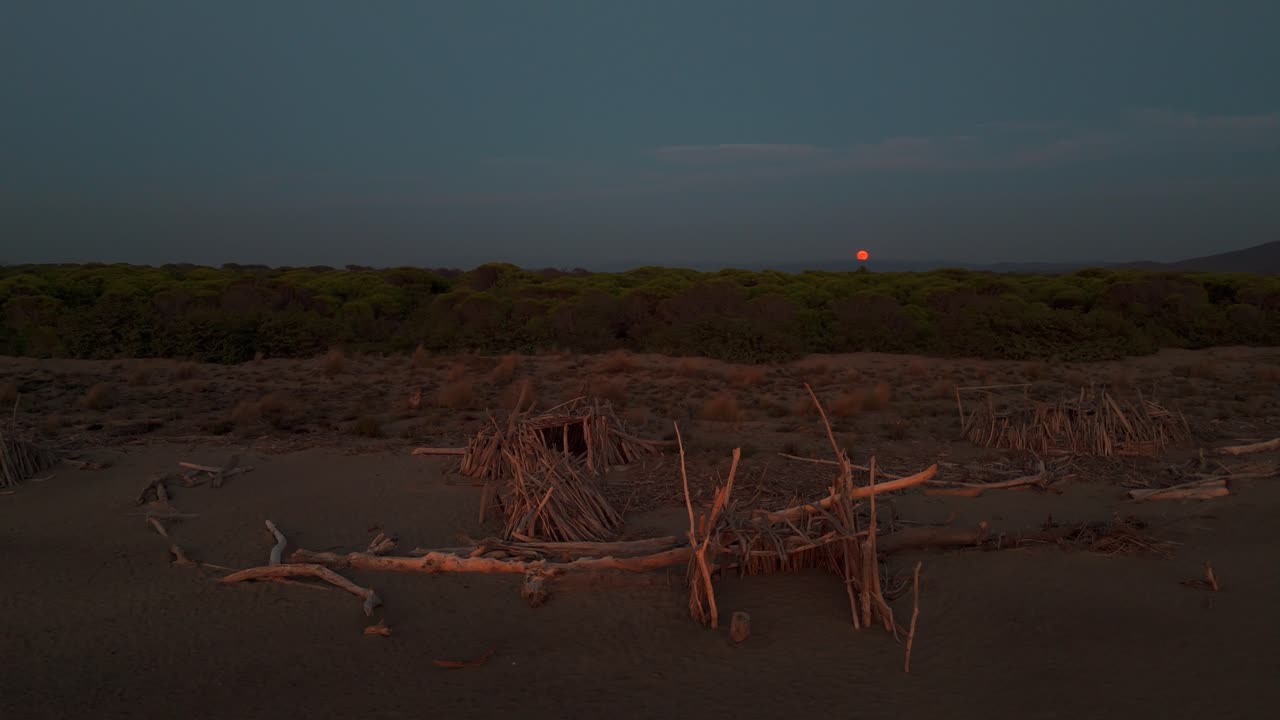 Spiaggia naturale con un tipì di legno in riva al mare al tramonto