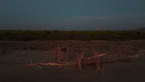 playa natural con un tipi de madera junto al mar durante la puesta de sol
