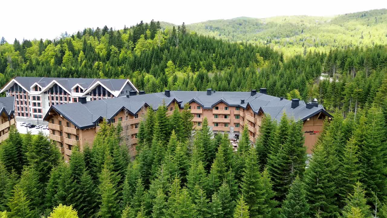 Luxury ski resort and mountain retreat in Kolasin valley surrounded by lush pine forest in summer near Biogradska Gora National Park, Swissotel resort, establishing drone shot