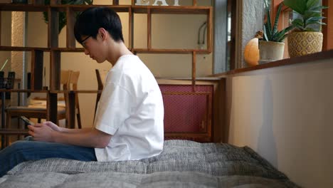 young man sitting alone in a cafe, playing with his phone