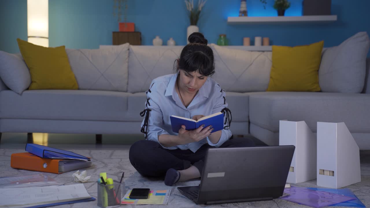 una trabajadora de oficina en casa leyendo un libro.