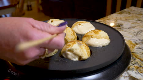 tuning ebelskivers as they bake in an electric dutch oven - close up