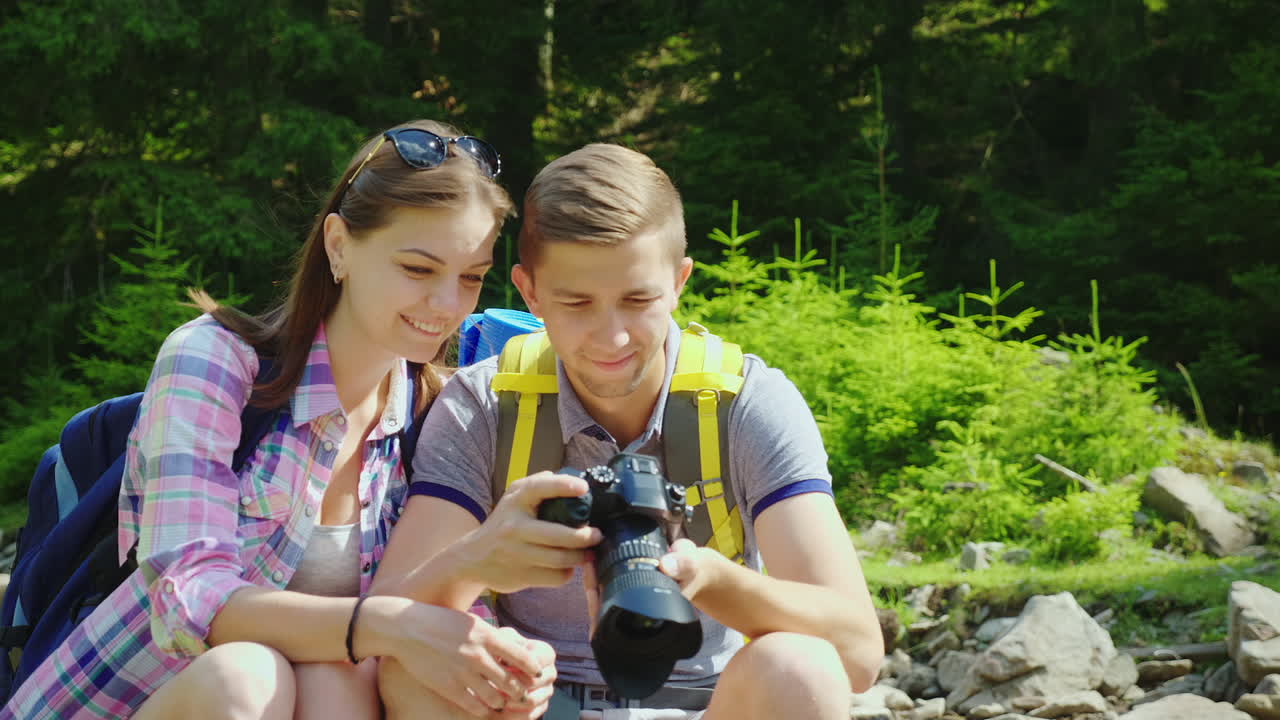 una feliz pareja de turistas mira las fotos capturadas en la cámara excelentes vacaciones y buen yo