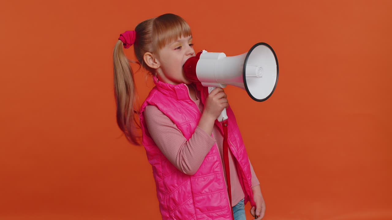 Bambina sorridente che parla con un megafono, proclamando notizie, annunciando a gran voce una pubblicità di vendita.