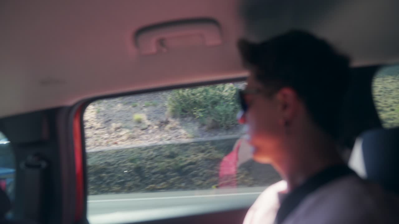 A person looking out the car window during a daytime journey