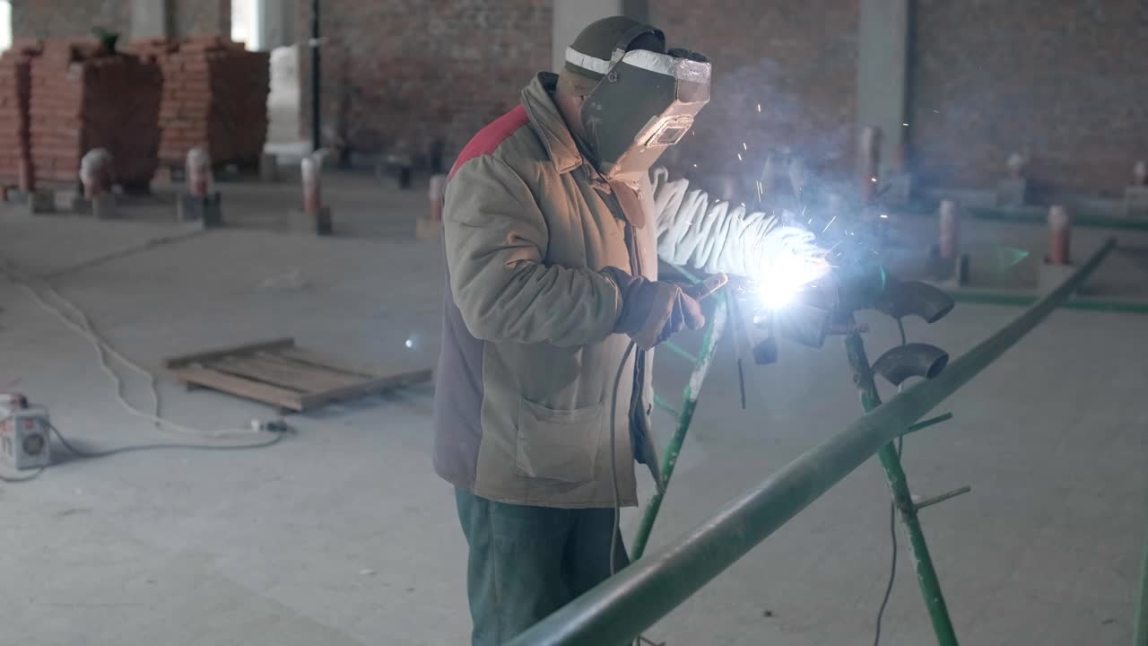 Professional welders are working in the factory wearing safety equipment. Metalwork manufacturing, industrial process.