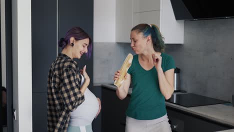 mujer embarazada y su madre en la cocina divirtiéndose y bailando en la cocina