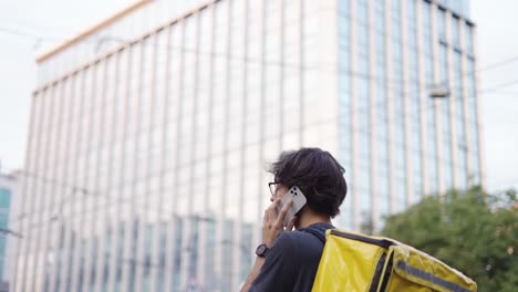 delivery man with backpack calling to a client on the city street