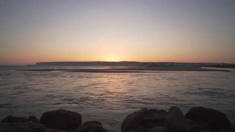 río que desemboca en el mar durante la puesta de sol en la costa de cádiz, españa