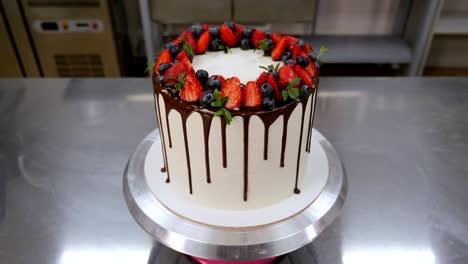 close-up of a cake with chocolate, strawberries, blueberries and mint leaves.