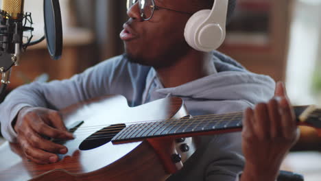 man playing acoustic guitar and singing in a home studio