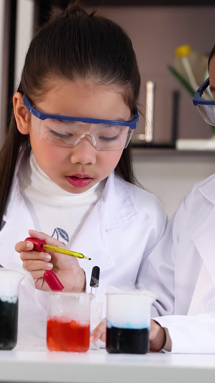 Siswa muda berjas lab menggunakan pipet dan es kering untuk eksperimen kimia yang penuh warna.
