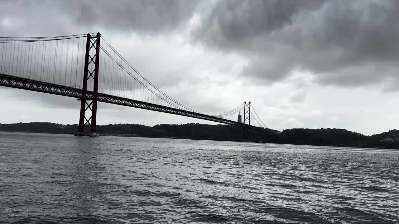 Moody Tagus River with Ponte 25 Abril under stormy clouds.