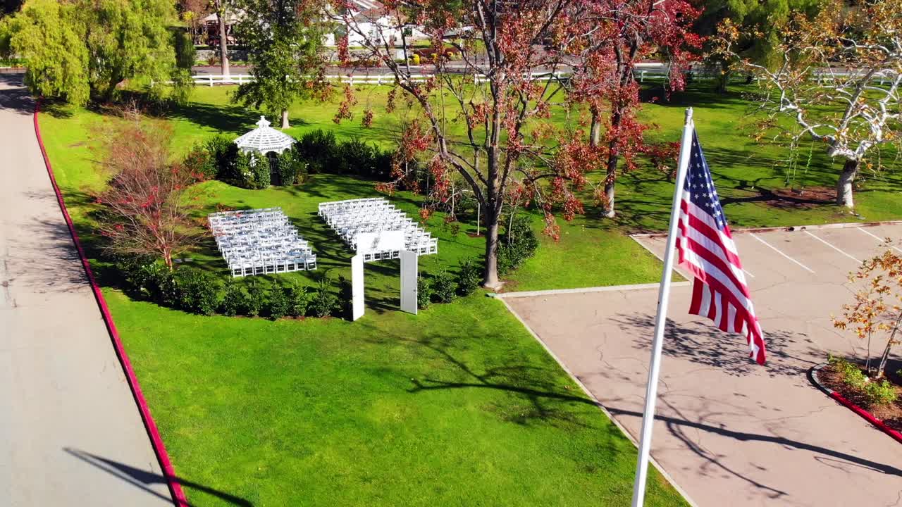 Aerial drone rising shot flying over an American Flag to reveal a military wedding venue.
