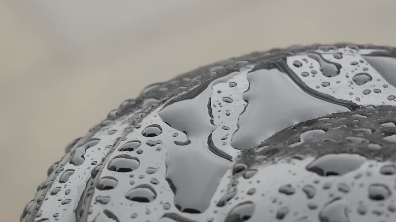 A handheld moment focused on the rain on top of a black post