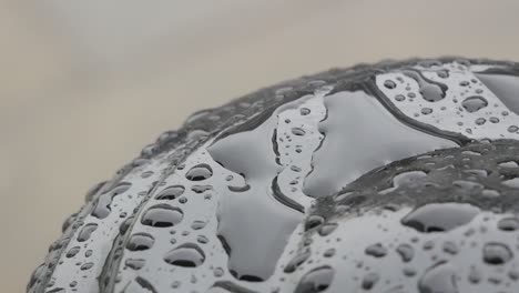a handheld moment focused on the rain on top of a black post