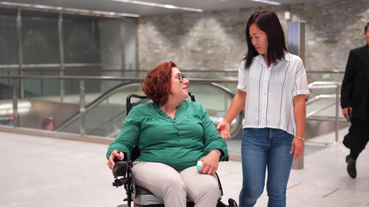 Woman in Wheelchair with Caregiver in Subway Station