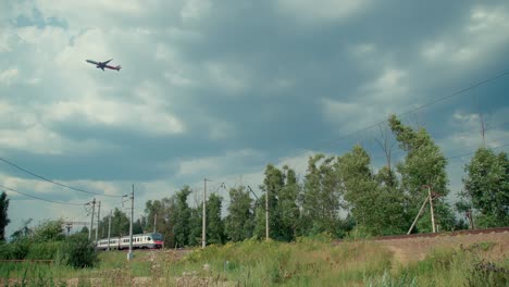 un tren lento en el ferrocarril y un avión volador