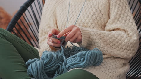 the hands of an unrecognizable girl knitting with blue wool