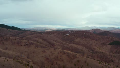 landscape view of curved forestry terrain with mountain slopes under cloudy sky. - aerial shot