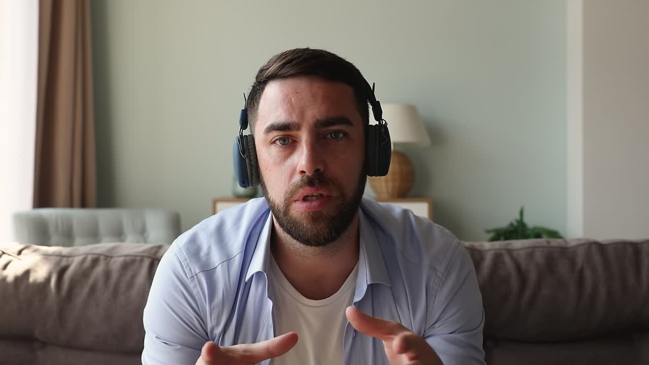 hombre con auriculares mira la cámara hace un discurso, vista de webcam