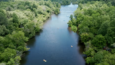 birds eye drone footage of people floating down the hiawassee river in inner tubes in tennessee during the summer months.