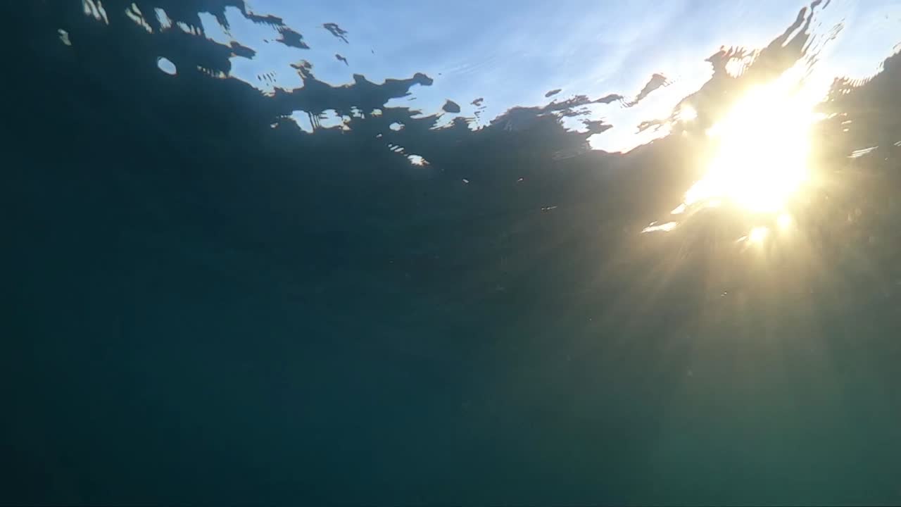 imágenes submarinas en cámara lenta del casco del barco pasando muy cerca con la luz del sol brillando a través del agua