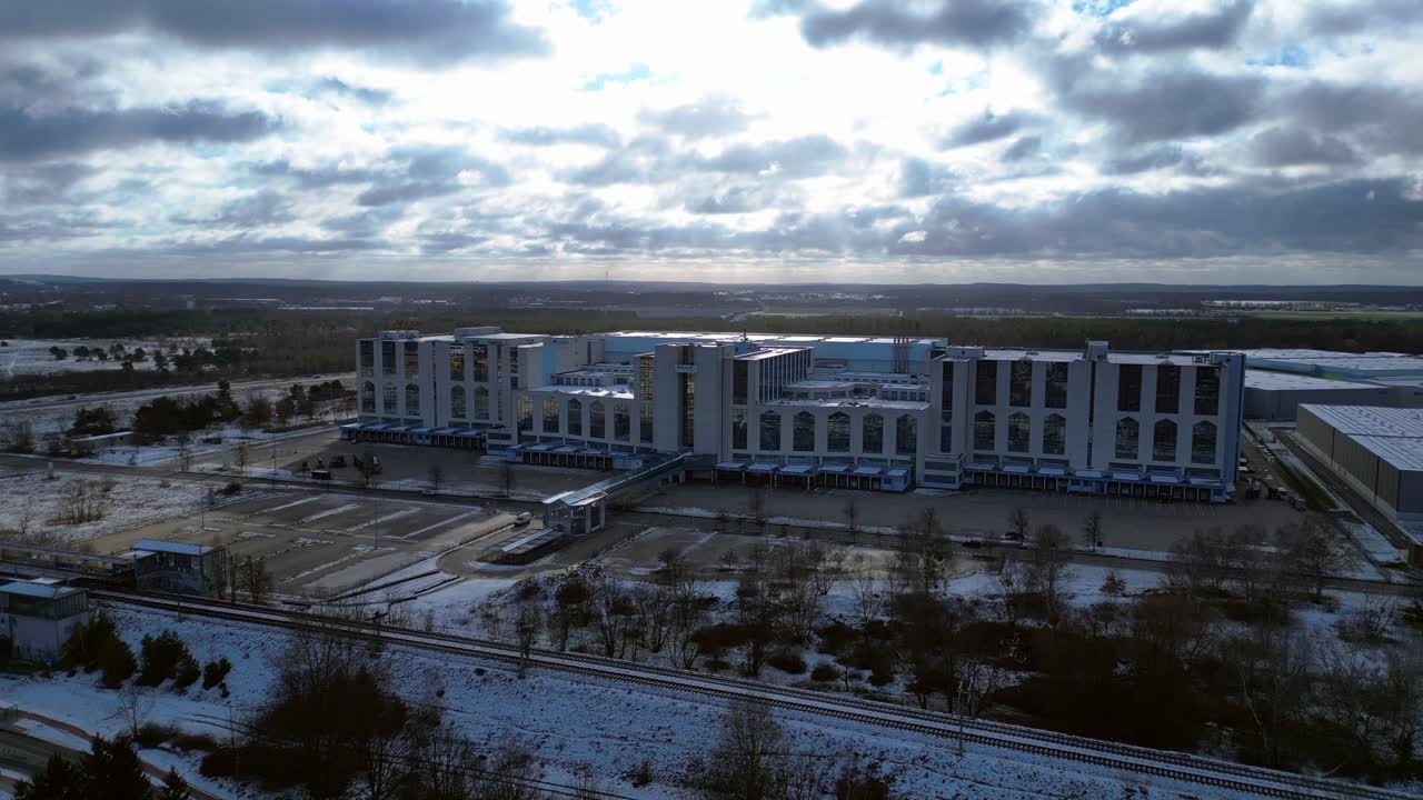 Large distribution center with loading docks and parking lot under a cloudy sky in winter. Amazing aerial view flight panorama overview drone