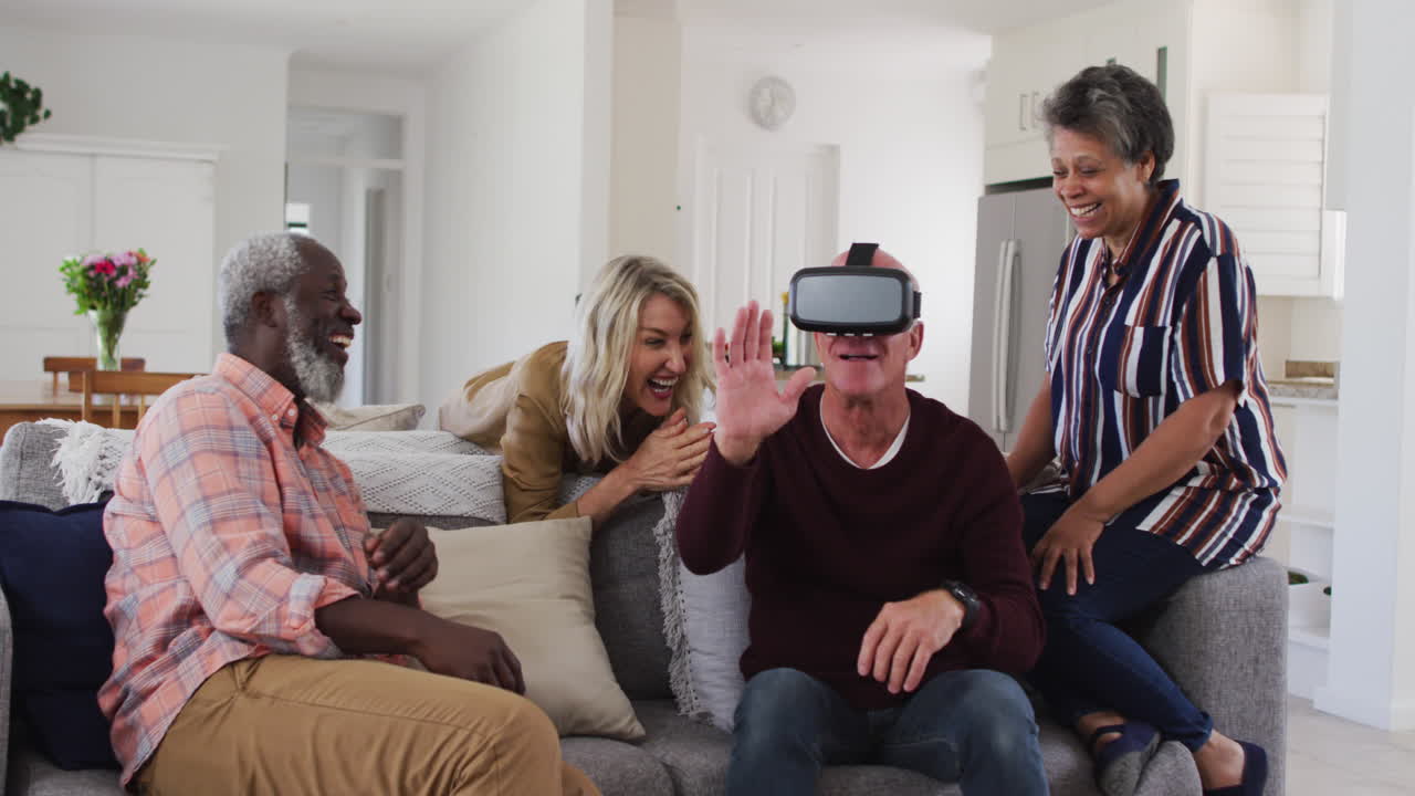 Two diverse senior couples sitting on a couch caucasian man is using vr googles