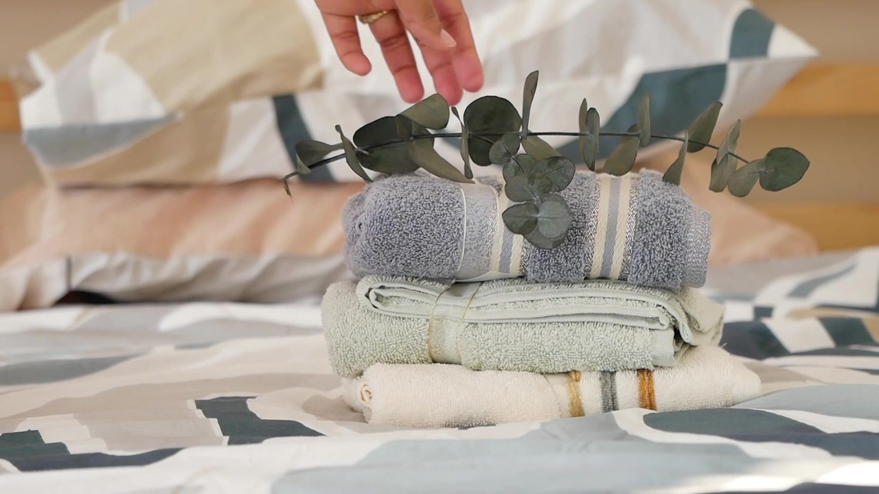 Stack of Folded Towels on a Bed with Eucalyptus Branch