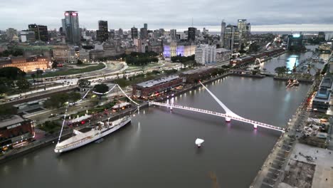 avión no tripulado vuela sobre puerto madero muelle, puente de la mujer en la ciudad de buenos aires argentina famoso destino de viaje del canal de agua al anochecer