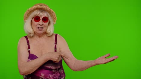 senior woman in swimsuit pointing at green screen