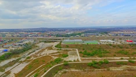 Drone-footage-of-the-flood-plain-with-shops,-car-parks-and-road-or-highway-of-to-the-sides