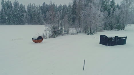 seguimiento lento y constante en toma de cabaña de madera y sauna rodeada de árboles en medio de la nada con nieve recién cubierta