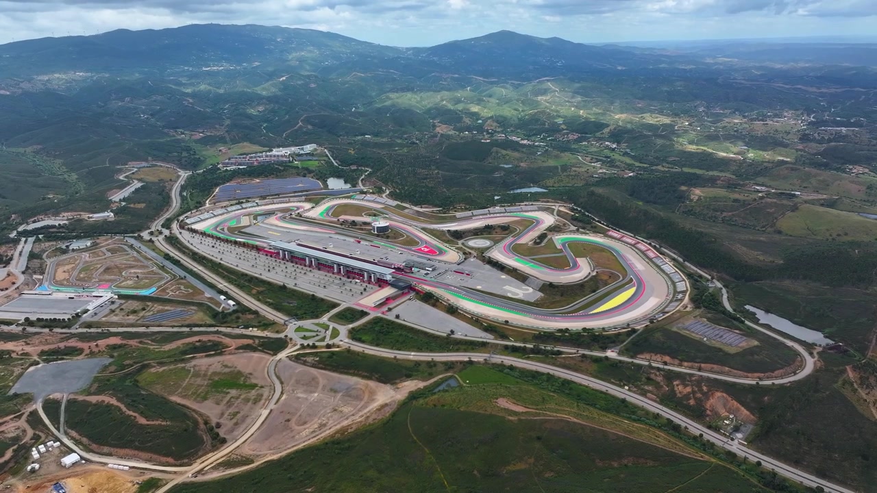 La vista aerea mostra il Circuito Internazionale dell'Algarve con veicoli da corsa in pista. Diverse attività di motorsport si svolgono su questa struttura professionale. Il circuito supporta molteplici formati di gara.