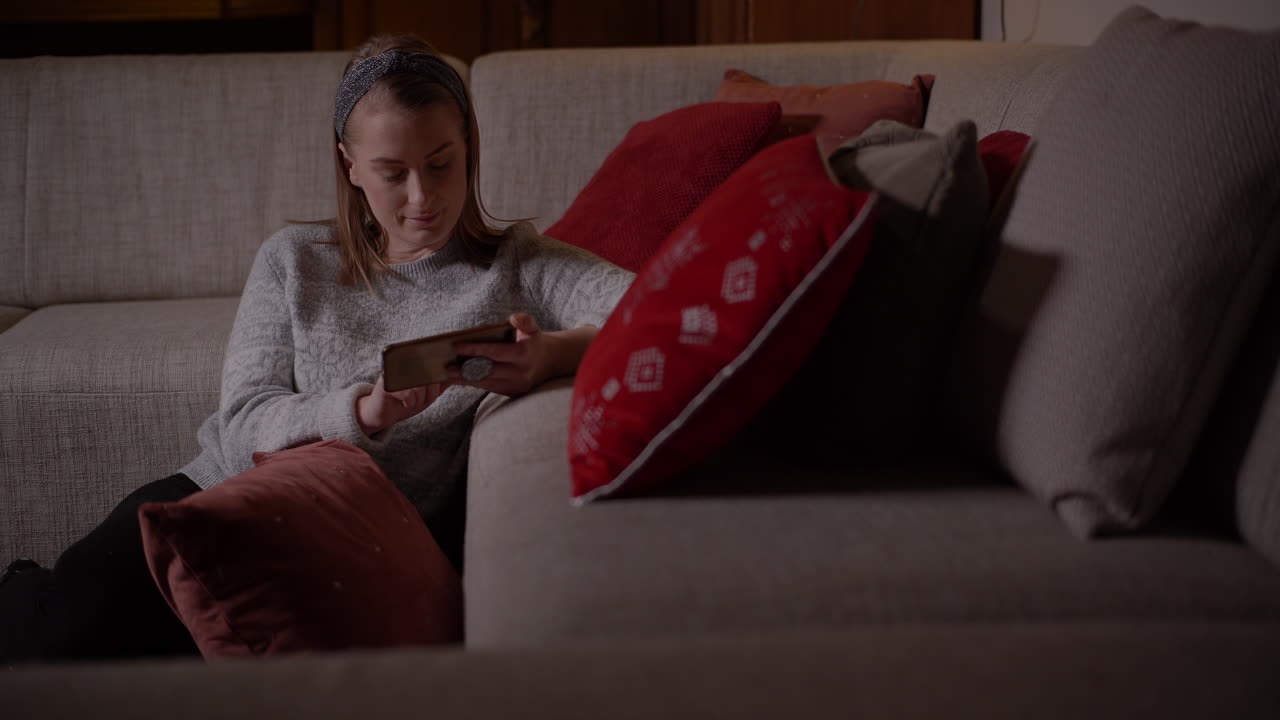 Young Woman Browsing Social Media On Smartphone At Home 4