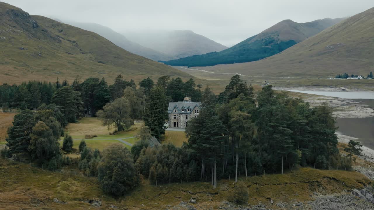 Circle right view of Loch Cluanie and lone manor in the Scottish Highlands, Scotland, with serene water and hills on overcast day