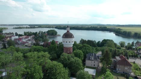 Torre-De-Agua-En-Ełkuwieża-W-Ełk,-Torre-De-Agua-Ubicada-En-La-Ciudad-De-Elk-En-Polonia-Con-El-Lago-Al-Fondo