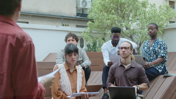 Team che ascolta il project manager durante una riunione di lavoro all'aperto