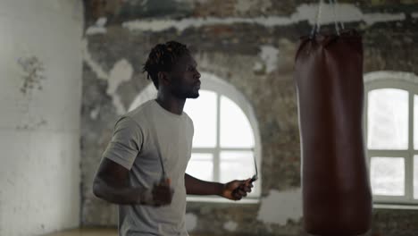 african american man skipping the rope in and empty hall with large windows