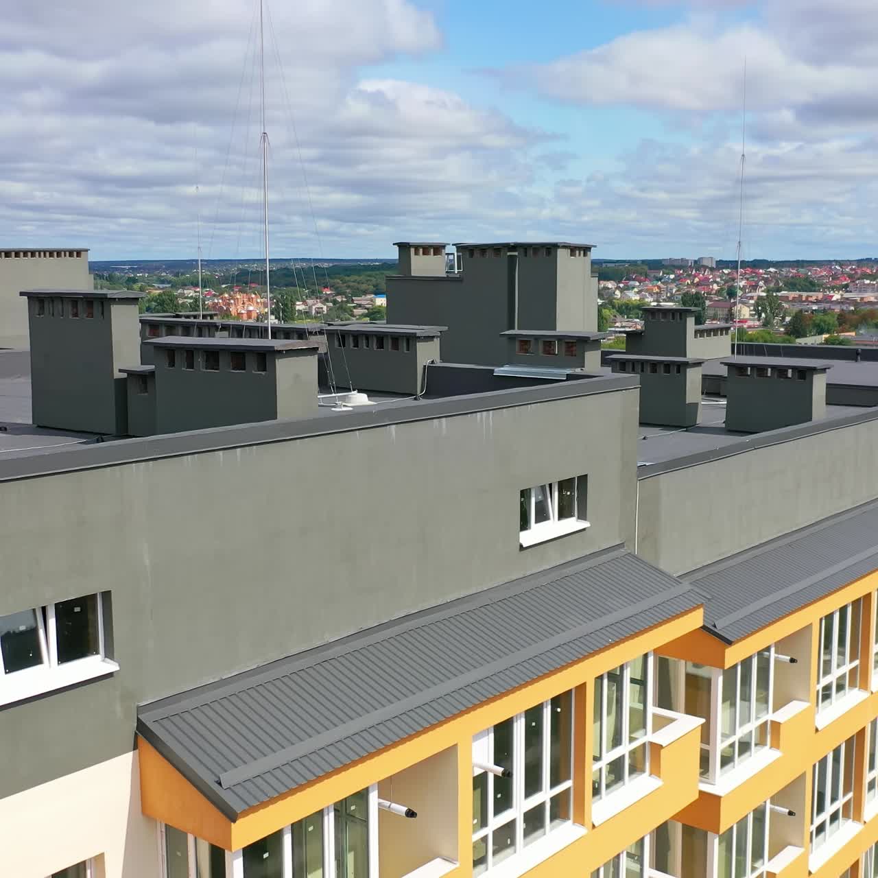 Modern architecture in the city. Tall building with grey roof in the city. New residential apartment building under blue sky. Camera rising