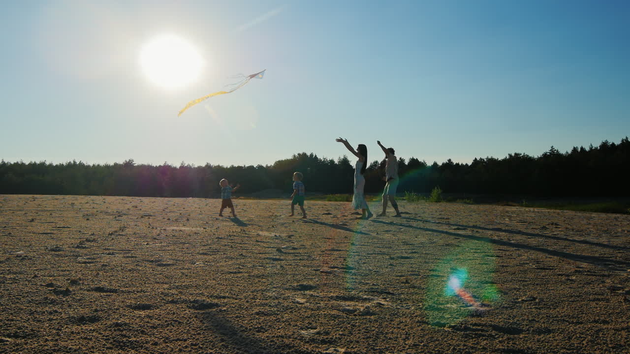 젊은 가족 - 엄마 아빠와 두 아들이 연을 가지고 놀고 있습니다.