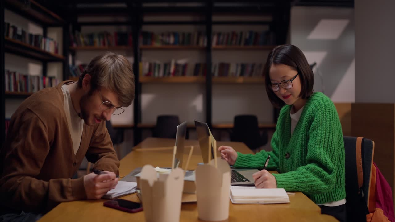estudiantes estudiando en la biblioteca por la noche
