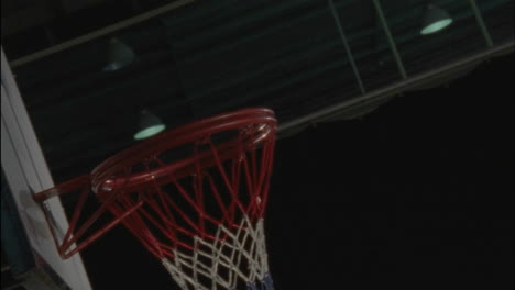 athlete landing a offensive rebound and scoring in a game of basketball
