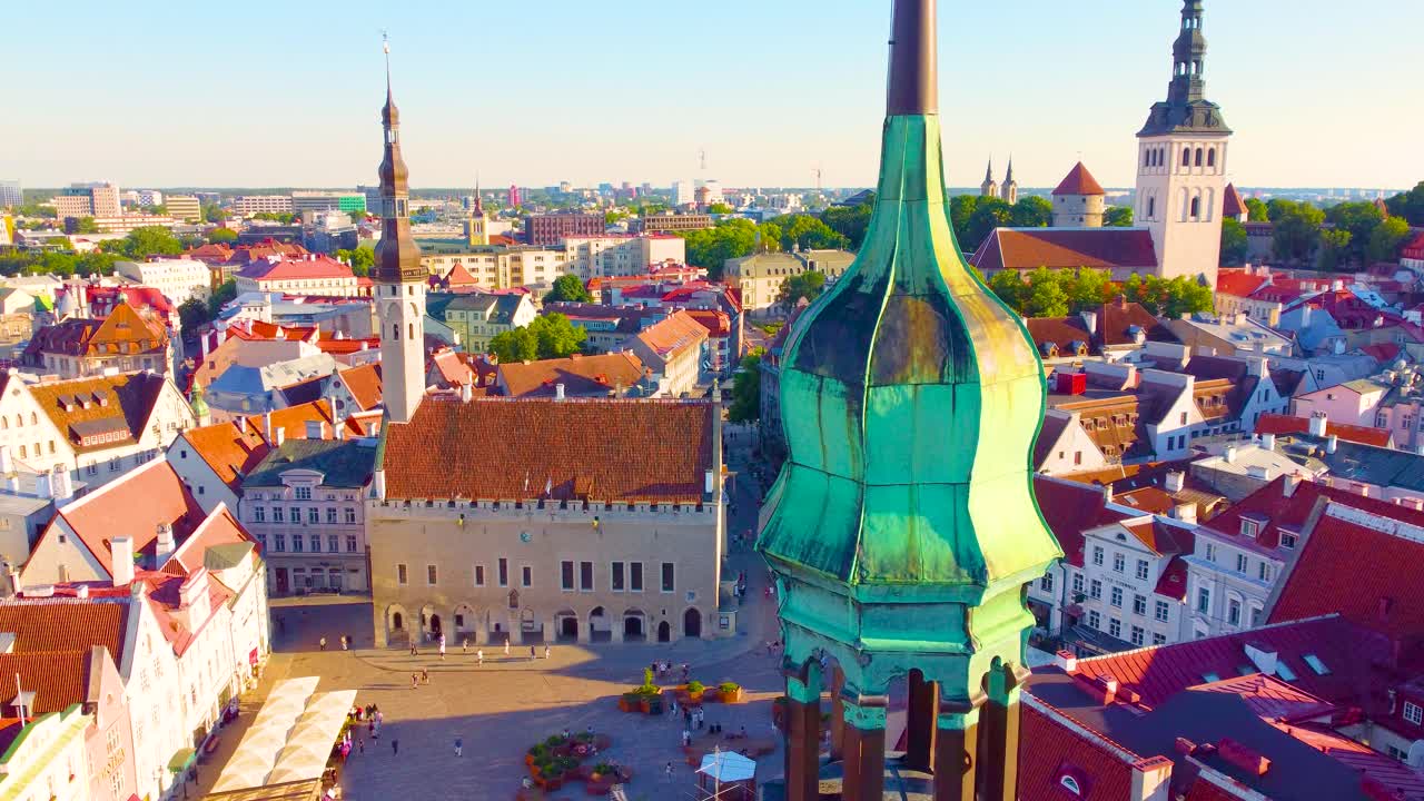 Town Hall Square in Tallinn, Estonia during sunset on a warm, sunny day. Aerial panning drone shot with views of restaurants and people