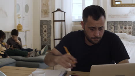 concentrated caucasian dad sitting at table and working.