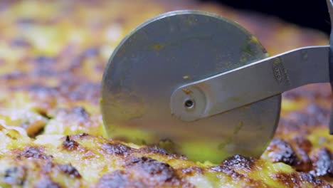 close up shot of a pizza cutter cutting delicious tasty home made gourmet pizza