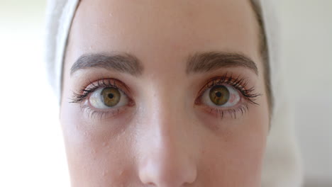 retrato de una mujer caucásica con una toalla en la cabeza abriendo los ojos en el baño en cámara lenta