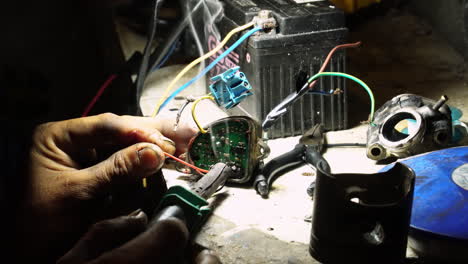 vista de cerca de la mano de un hombre soldando un equipo eléctrico en una tienda interior