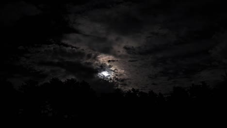 Superluna-Brillando-Por-La-Noche-En-El-Cielo-Oscuro-Sobre-El-Bosque-De-árboles,-Las-Nubes-Se-Mueven-Rápidamente-Sobre-Montañas-De-Hermoso-Fondo-Romántico